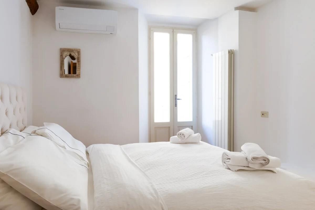Una camera d'albergo con un letto, una finestra e una porta.