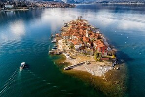 Une vue aérienne d’une petite île avec un ensemble de bâtiments, un quai et un bateau sur l’eau.