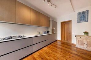 A modern kitchen with wooden cabinets, a built-in stove, and a wooden floor. - Italian Lakes 2 bedroom Apartment with fresco (Lesa)
