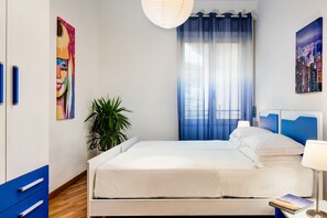 Un dormitorio moderno con una cama, una planta en maceta y obras de arte en las paredes.