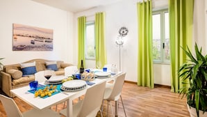 A dining area with a table set for four, a sofa, and a painting on the wall.