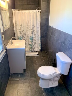 Un baño pequeño con cortina de ducha, lavamanos e inodoro.