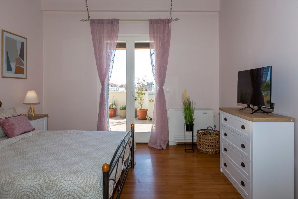 Una camera da letto con un letto, una cassettiera, una televisione e vista sull'esterno.