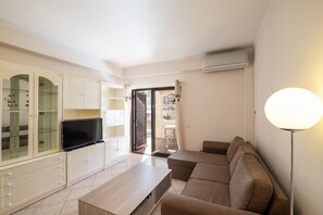 A living room with a sofa, TV, cabinet, and a lamp.