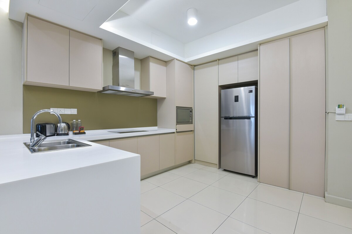 A modern kitchen with a stainless steel refrigerator, a built-in oven, and a sink with a faucet.