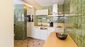 Une cuisine compacte avec des murs recouverts de carreaux verts, un four à micro-ondes, un évier et un plan de travail sur lequel se trouve un saladier.