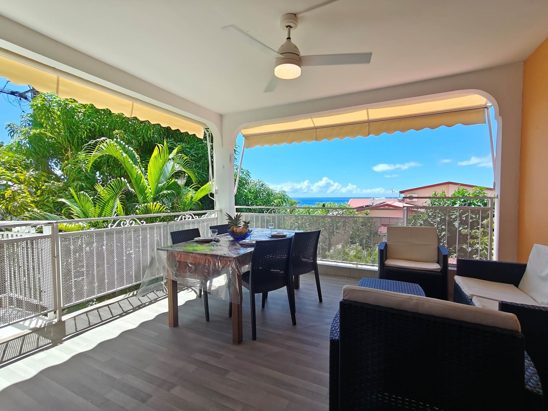 A balcony with a table and chairs, a ceiling fan, and a view of the ocean.