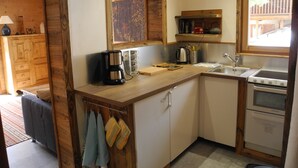 Una cocina compacta con armarios de madera, una cafetera, un hervidor y un lavamanos.