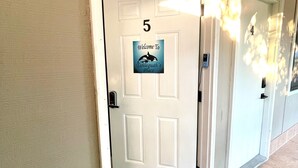 L’entrée d’un hôtel, avec les portes numérotées 4 et 5, un panneau d’accueil et un paillasson.