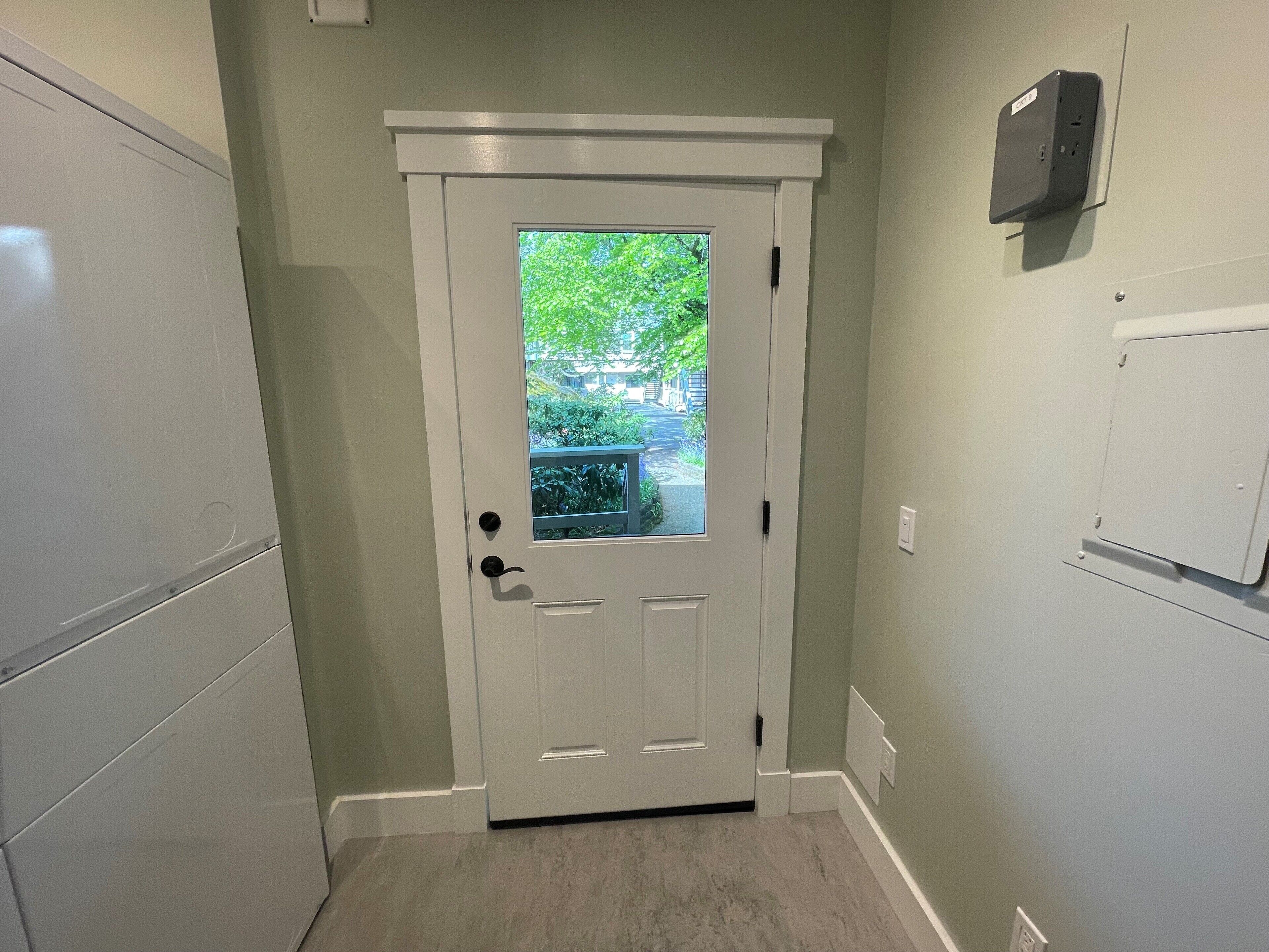 A white door with a glass panel, a small window, and a doorbell.
