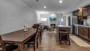 Una cocina moderna con comedor, armarios de madera, electrodomésticos de acero inoxidable y chimenea.
