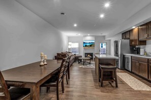 Una cocina moderna con comedor, armarios de madera, electrodomésticos de acero inoxidable y chimenea.