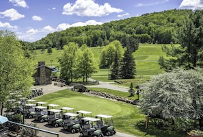 A golf course with a clubhouse, a parking area with golf carts, and surrounding greenery. - Spacious Townhome with Fireplace (Ellicottville)