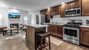 Una cocina moderna con armarios de madera, electrodomésticos de acero inoxidable, una isla central y una chimenea.