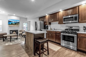 Una cocina moderna con armarios de madera, electrodomésticos de acero inoxidable, una isla central y una chimenea.