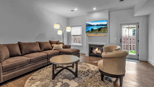 Una sala de estar con sofá, sillón, mesa de centro, chimenea, televisor y vistas al exterior.
