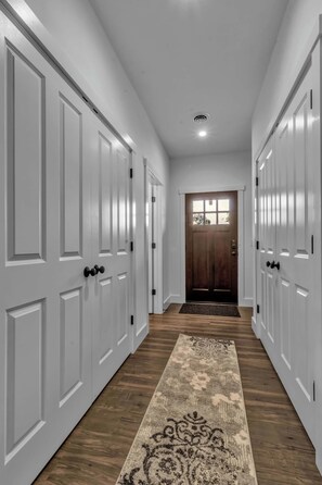 Un pasillo con puertas blancas, suelo de madera y un tapete estampado.