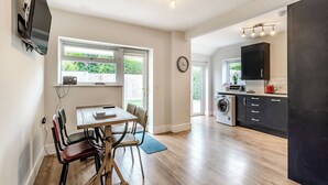 Una cocina moderna con zona de comedor, suelo de madera y un amplio ventanal.