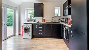 Una cocina moderna con armarios oscuros, lavadora integrada, microondas y un lavamanos.