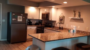 A modern kitchen with granite countertops, stainless steel appliances, and a central island with bar stools.