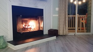 A living room with a fireplace, a sliding glass door, and a dark leather sofa.