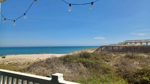 A beach view with a wooden boardwalk and string lights.