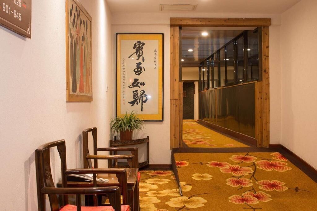 A hallway with wooden chairs, a potted plant, and a carpet with a floral pattern.