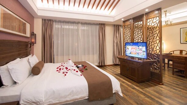 A hotel room with a bed, a TV, a wooden cabinet, and a dining area. - James Joyce Coffetel (Xi'an)
