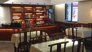 A restaurant with wooden tables and chairs, a bar area with shelves of bottles, and a television screen. - James Joyce Coffetel (Xi'an)