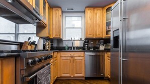 Una cocina moderna con armarios de madera, electrodomésticos de acero inoxidable y una encimera negra.