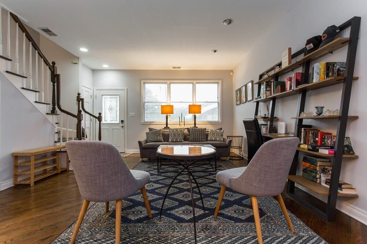 Een woonkamer met een bank, twee fauteuils, een salontafel en een boekenkast.