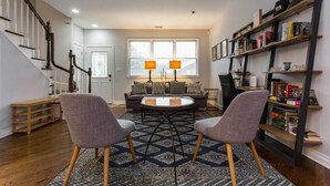 Una sala de estar con un sofá, dos sillones, una mesita de centro y una estantería.