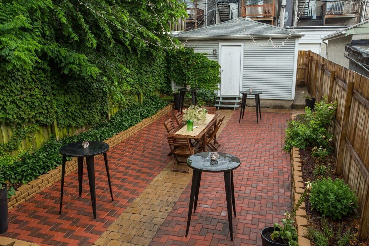 A patio with a brick floor, a wooden table, and two chairs.