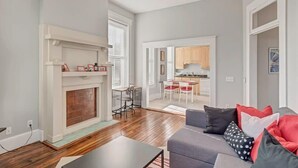 A spacious living room with a fireplace, a dining area, and a kitchen visible through an open door.