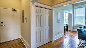 A room with hardwood flooring, a white door, a black couch, and a window with blinds. - Airy apartment in historic Springfield (Jacksonville)