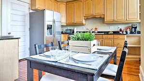 A modern kitchen with wooden cabinets, a stainless steel refrigerator, and a dining table set for four. - Airy apartment in historic Springfield (Jacksonville)
