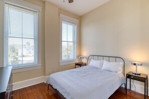 A bedroom with a bed, two bedside tables, and two windows with blinds. - Open & Bright - 5 min drive to TIAA Bank field (Jacksonville)