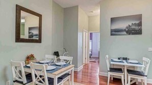A dining area with white chairs and a wooden table, a mirror on the wall, and a painting. - Stylish 2 BR apartment - perfect for relaxing! (Jacksonville)