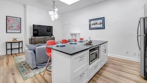 Cucina moderna con isola centrale, mobili bianchi e piano di lavoro nero.