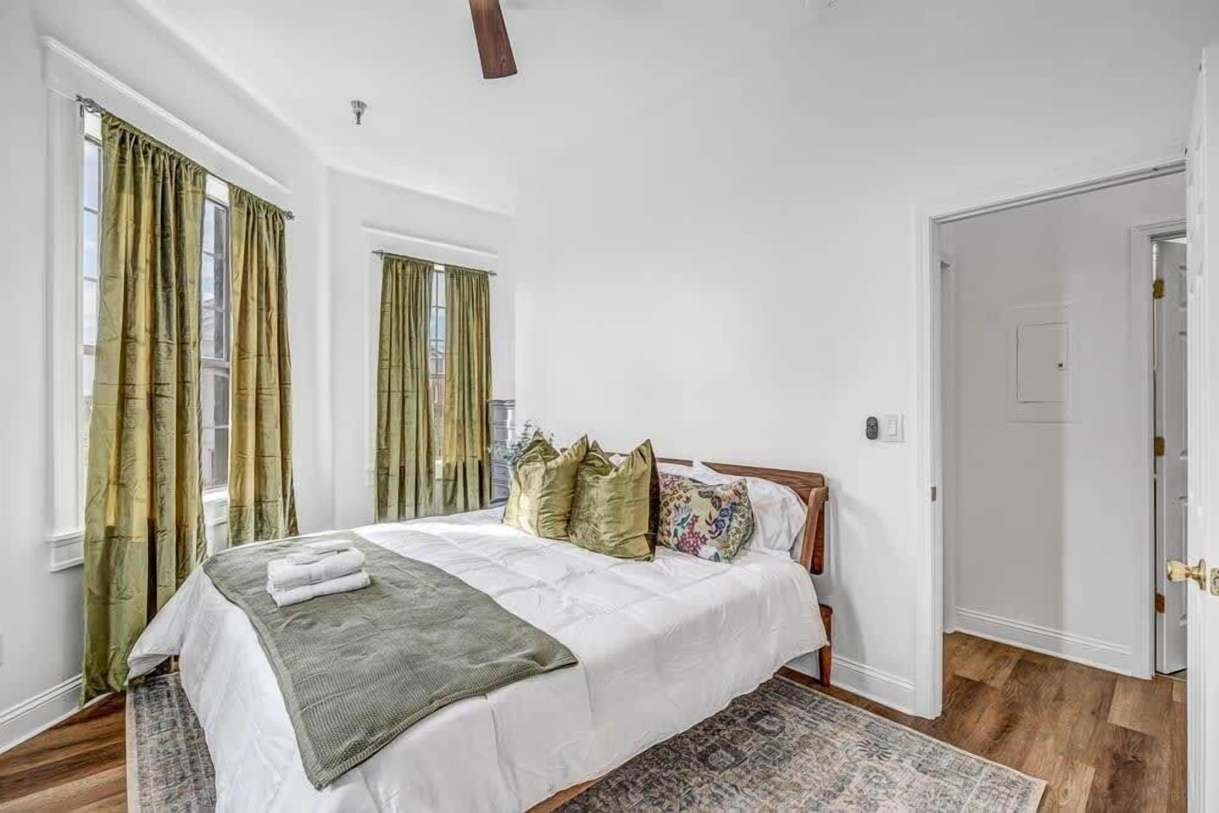 A bedroom with a bed, curtains, a rug, and a door.