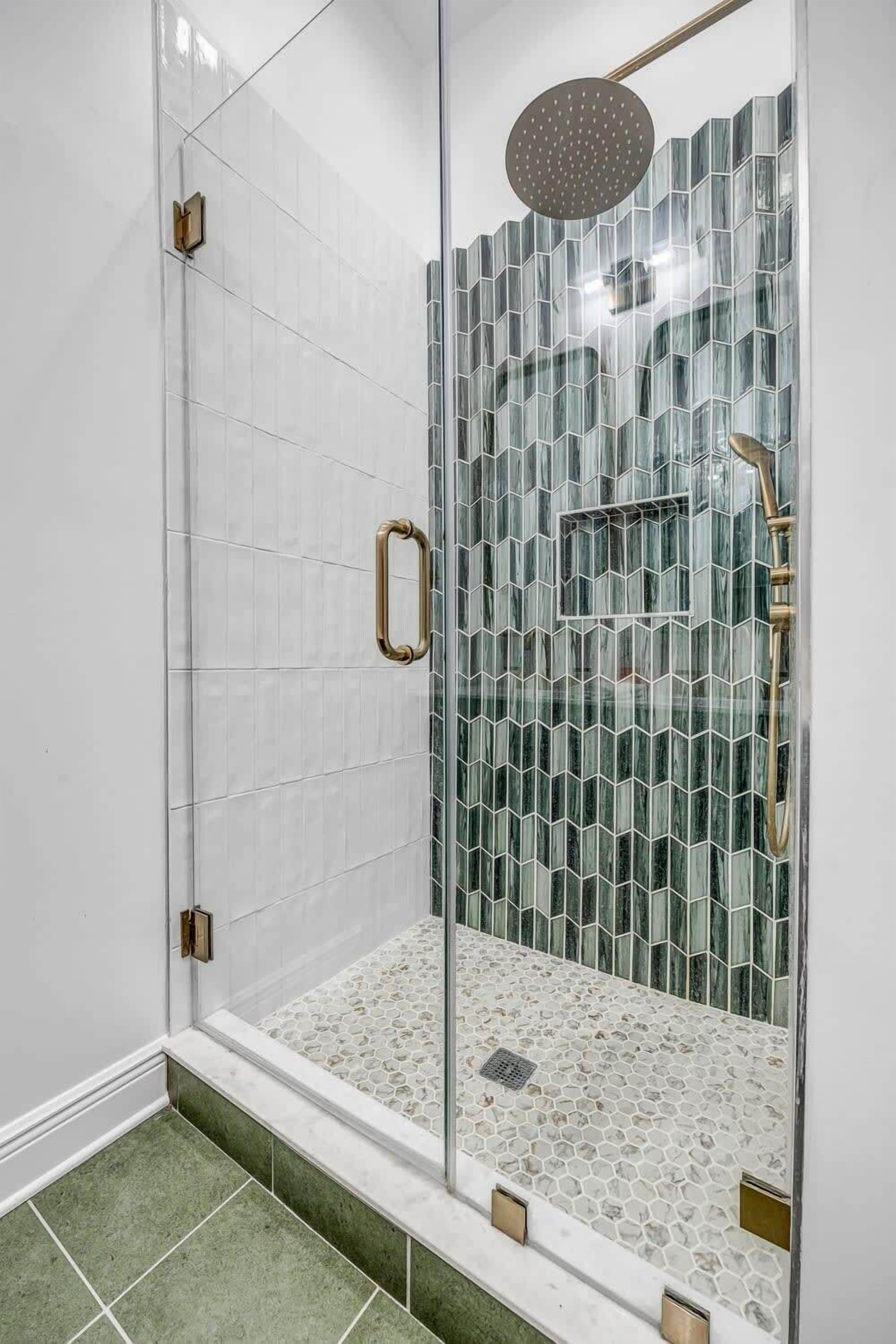 Eine gläserne Duschkabine mit Regendusche, kleinem Fenster und Handlauf.