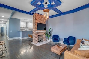 Un salón comedor amplio con chimenea de ladrillo, paredes de acento azul y muebles modernos.