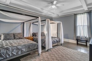Un dormitorio con cama con dosel, ventilador de techo y alfombra estampada.
