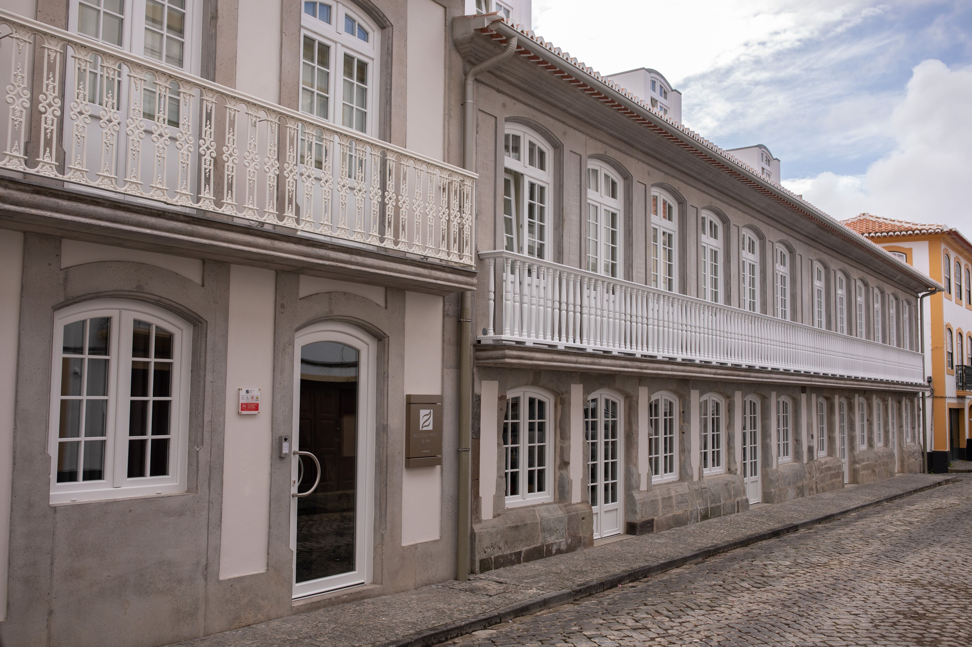 A historic building with a stone facade, multiple windows, and a decorative balcony.