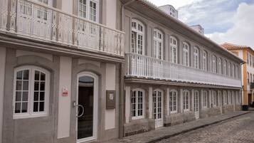 A historic building with a stone facade, multiple windows, and a decorative balcony.