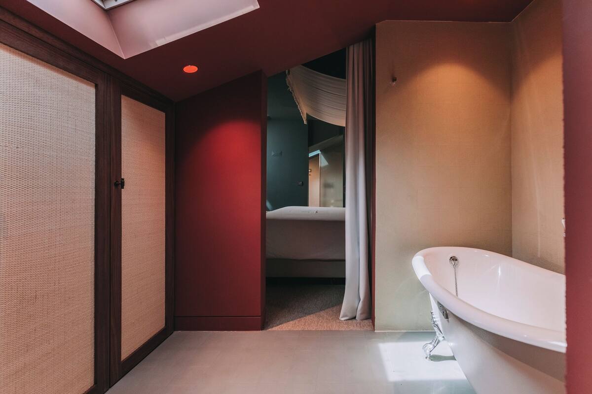 A modern bathroom with a freestanding bathtub, a walk-in shower, and a sliding door leading to a bedroom.