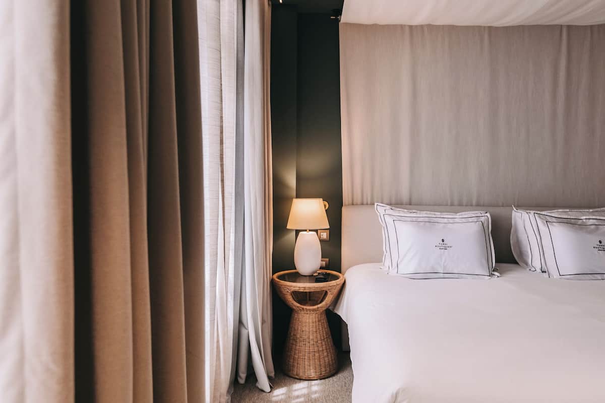 A bedroom with a bed, a lamp, and curtains.