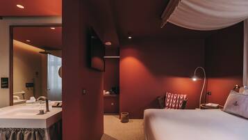 Une chambre d’hôtel avec un lit, une table de chevet, une lampe et un miroir.