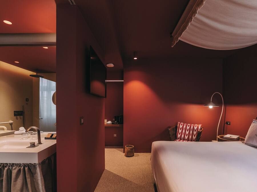 Une chambre d’hôtel avec un lit, une table de chevet, une lampe et un miroir.