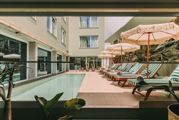 Alberca techada, alberca al aire libre y sombrillas en la alberca